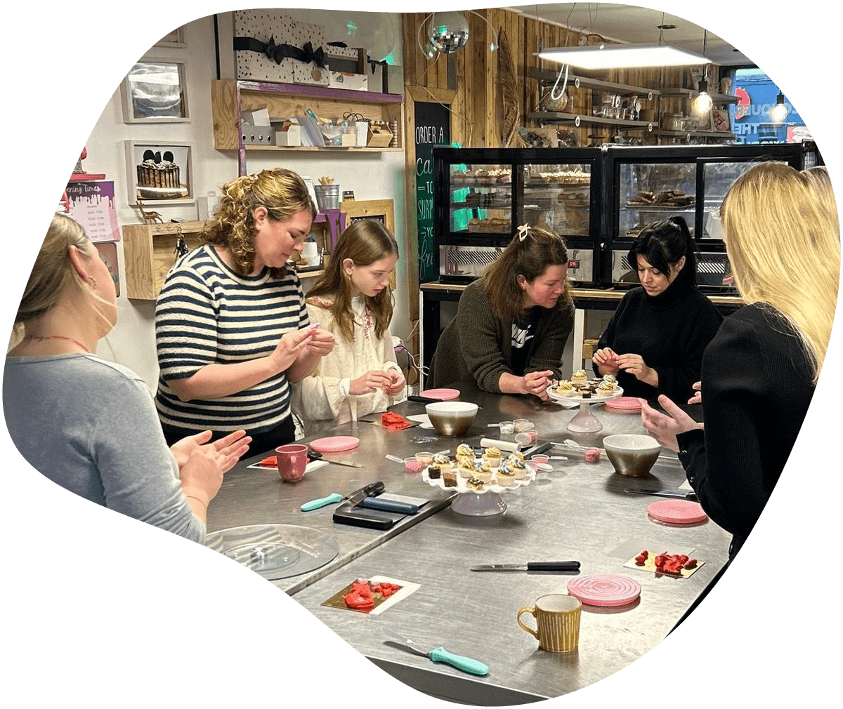 Groepsworkshop bij Bake My Day Groningen waar deelnemers leren taarten en cupcakes decoreren in de winkel.