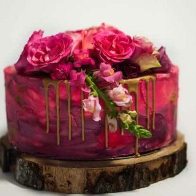 Layer cake met roze en paarse botercrème en verse bloemen, handgemaakt door Bake My Day Groningen.