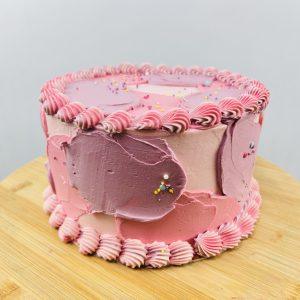 Roze taart met decoratie en bloemen van Bake My Day Groningen.